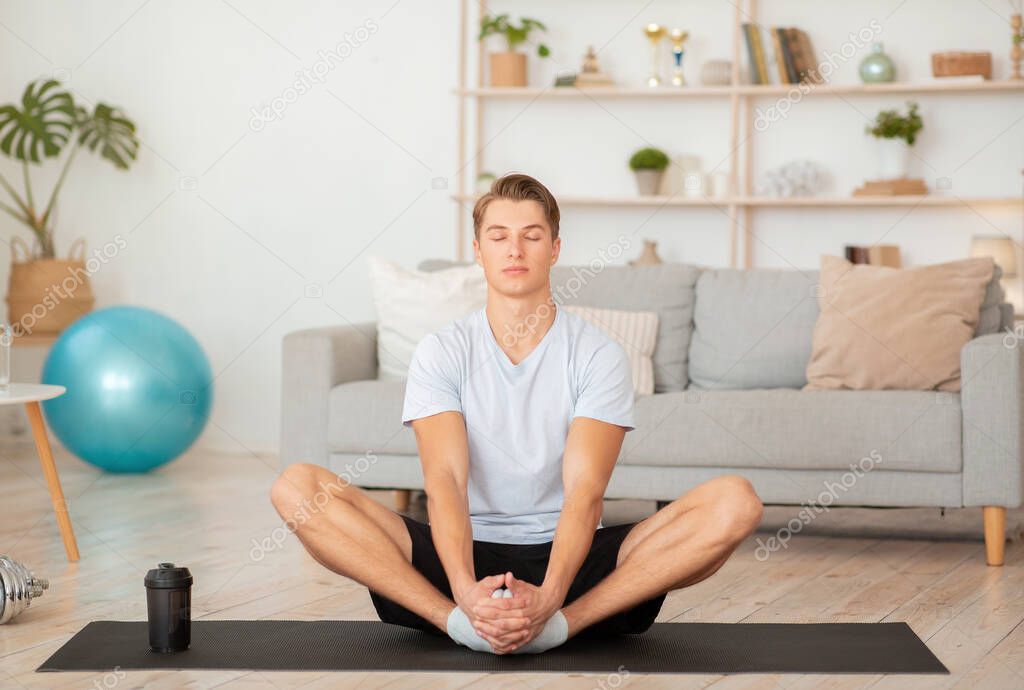 Modern sports at home in self isolation. Guy with closed eyes meditates or practices yoga