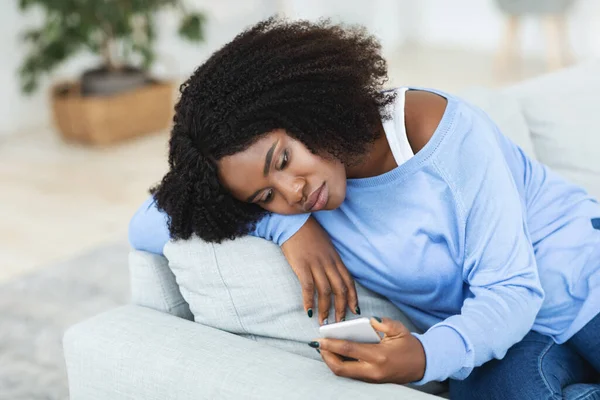 Frustrierte Frau checkt Handy auf der Couch — Stockfoto