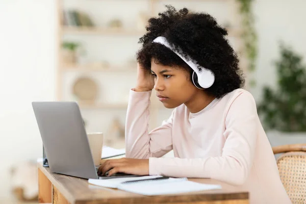 Чорна дівчина-підліток в ноутбуці вивчає онлайн сидячи вдома — стокове фото