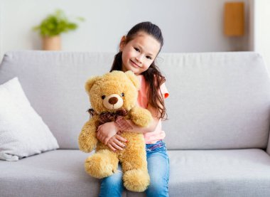 Koreli Kız Pozisyonu Evde oturan oyuncak ayıyı kucaklıyor