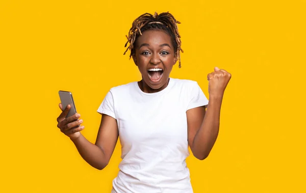 Szerencsés afrikai nő nyert lottó, kezében mobiltelefon — Stock Fotó