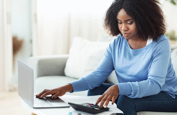 Kobieta korzystająca z kalkulatora i komputera w domu — Zdjęcie stockowe