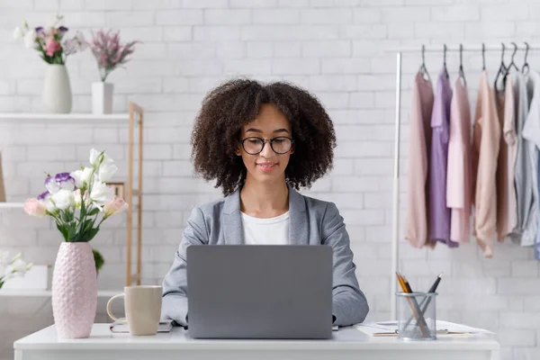 Ambitieuze zakenvrouw met bril aan het werk met laptop in interieur van fashion studio — Stockfoto