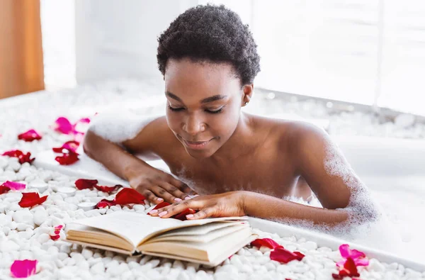 Free time and rest. African american girl in foam in bathroom reads book — Stock Photo, Image