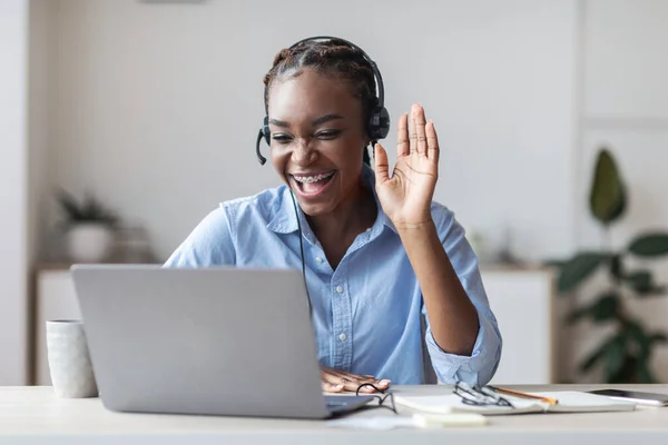 Rozmowa wideo. Uśmiechnięta czarna bizneswoman w słuchawkach mając konferencję internetową na laptopie — Zdjęcie stockowe