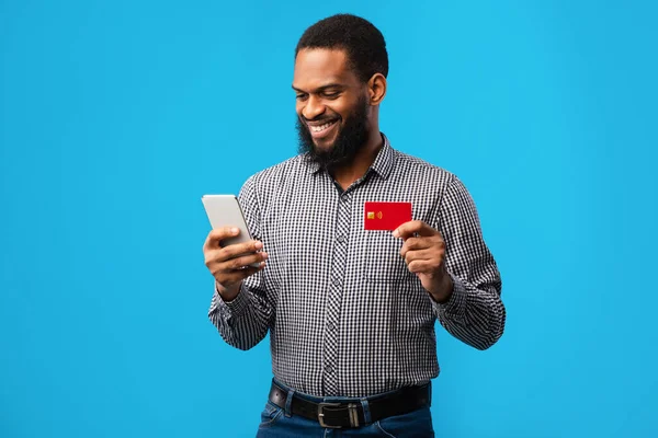 Zwarte man met creditcard en mobiele telefoon in de studio — Stockfoto