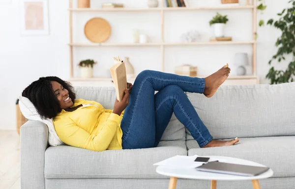 Ένα μαύρο κορίτσι διαβάζει ένα βιβλίο στο σπίτι. — Φωτογραφία Αρχείου