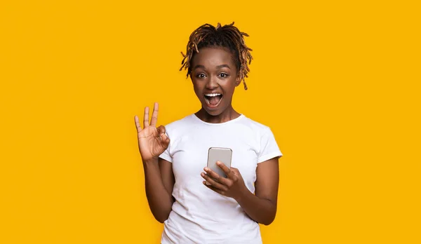 Menina preta emocional com smartphone mostrando tudo bem — Fotografia de Stock