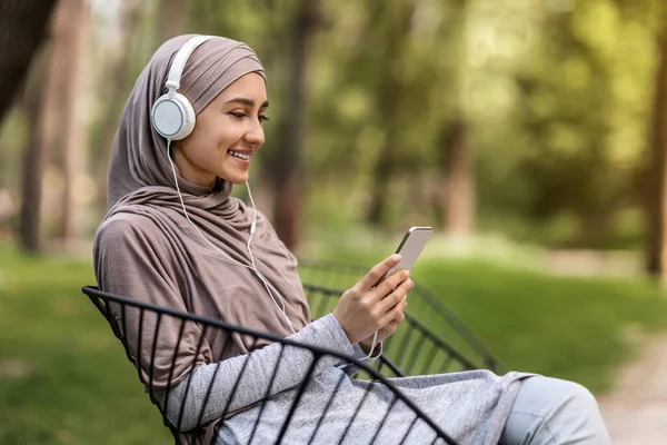 Sisi tampilan gadis arab mendengarkan musik di taman — Stok Foto