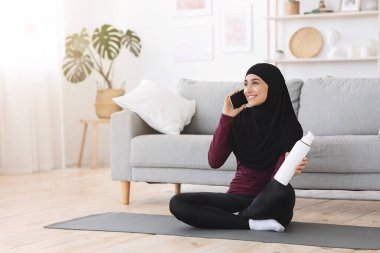 Evde eğitimden sonra tesettürlü mutlu bir Arap kadın cep telefonuyla konuşuyor.