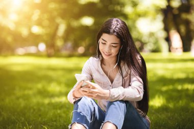 Hayalci Asyalı Kız En sevdiği şarkıları dışarıda akıllı telefon ve kulaklıkla dinliyor.