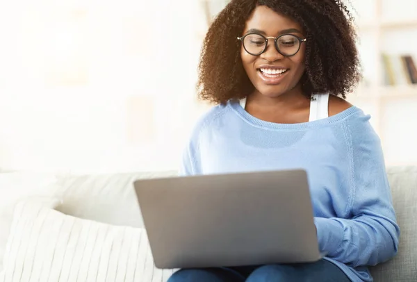 Sorrindo mulher negra sentada no sofá com pc — Fotografia de Stock