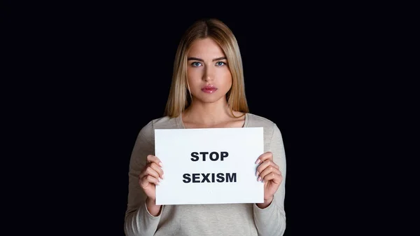 Igualdad de oportunidades para hombres y mujeres. Chica triste sostiene el signo con la inscripción stop sexism — Foto de Stock