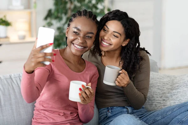 Vrolijke Afrikaanse besties nemen selfie samen thuis — Stockfoto