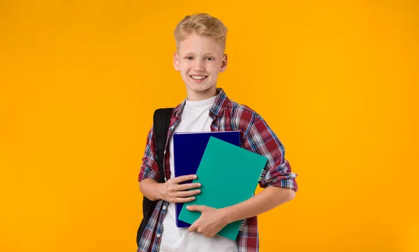 Sonriente adolescente posando con libros de texto en el estudio — Foto de Stock