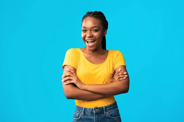 Alegre Africano Millennial menina posando cruzando as mãos sobre fundo azul — Fotografia de Stock