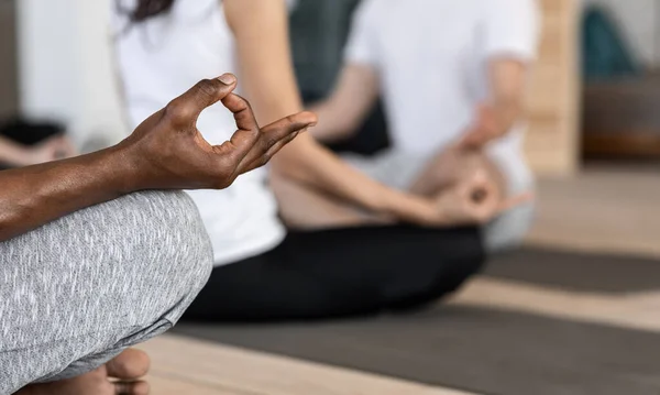 Крупный план черного мужчины медитирующего в позе лотоса на уроке групповой йоги — стоковое фото