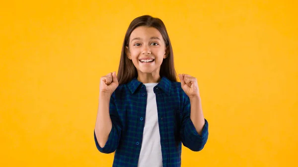 Little girl celebrating over yellow studio background — ストック写真