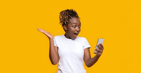 Amazed black girl looking at mobile phone — Stock Photo, Image