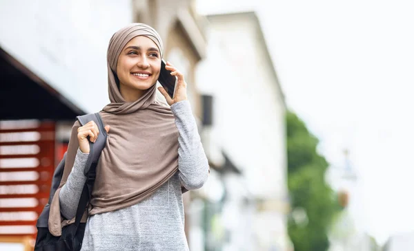 Estudiante musulmana positiva con mochila hablando en smartphone — Foto de Stock