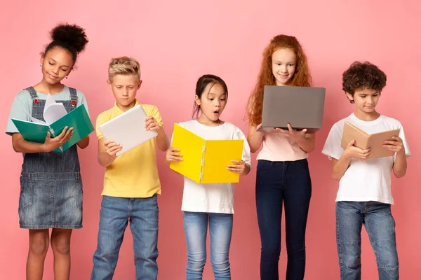 De vuelta a la escuela. Niños multiétnicos con gadgets, libros y cuadernos sobre fondo rosa —  Fotos de Stock