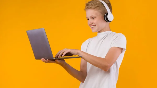 快乐的青少年站在笔记本电脑旁打字 — 图库照片