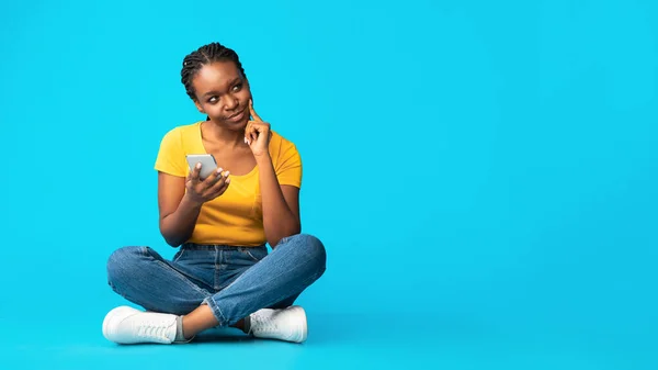 Thoughtful African American Girl Sitting Using Cellphone, Blue Background — Stock Photo, Image