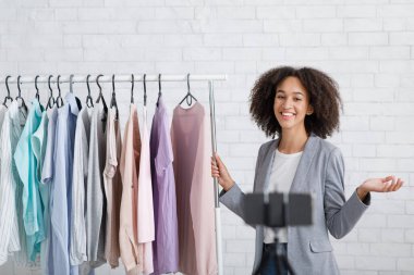 Moda ve uzaktan giyim tarzı. Gülümseyen kadın iç mekanda stil kurallarını anlatıyor