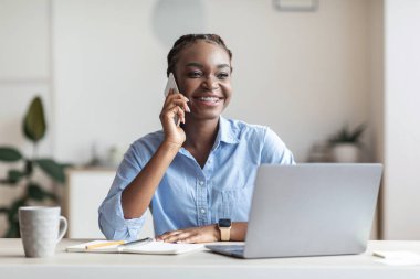 İş yerinde cep telefonuyla konuşan siyahi bir girişimci müşteriye danışmanlık yapıyor.