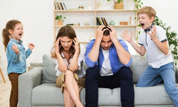 Uncontrollable Children Shouting Loudly Misbehaving Standing Near Desperate Parents Indoor — Stock Photo, Image