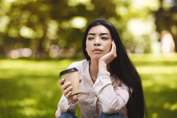 Кава на відкритому повітрі. Pensive азіатська дівчина насолоджуючись takingaway напій в Park — стокове фото