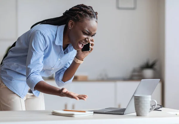 Problemas en el trabajo. Mujer de negocios negra estresada hablando por teléfono celular y gritando —  Fotos de Stock