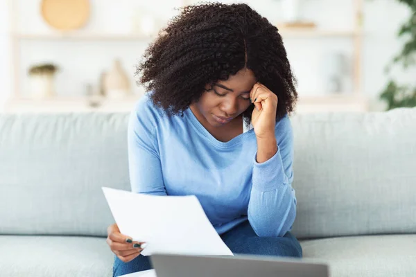Traurige schwarze Frau hält Papiere mit Laptop in der Hand — Stockfoto
