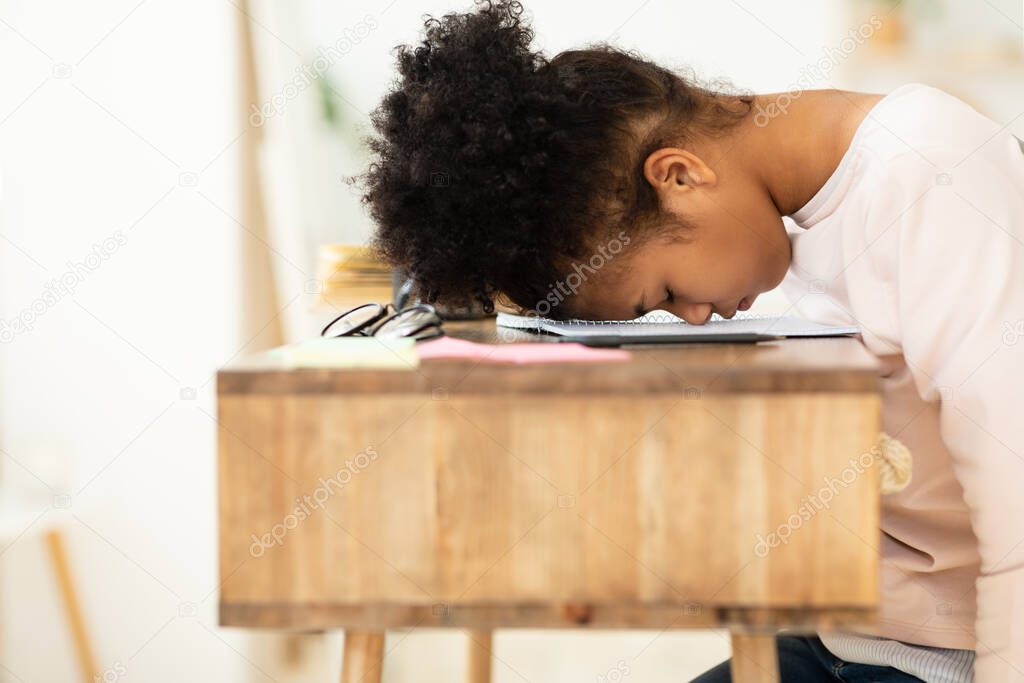 Overworked African Girl Resting Head On Desk Sitting Indoor