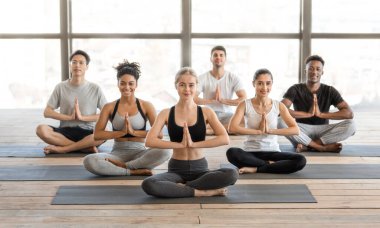 Uluslararası Yoga sınıfı. Lotus Pozisyonunda Oturan Sportif Milenyum Halkı Grubu