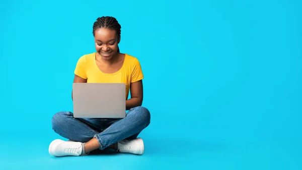 Boldog fekete lány Laptop használata ül a kék háttér, Panoráma — Stock Fotó