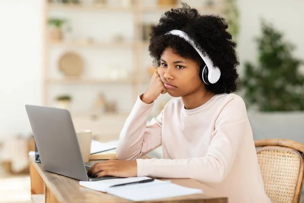 Evde dizüstü bilgisayar başında oturan sıkılmış Afrikalı Amerikalı genç kız — Stok fotoğraf