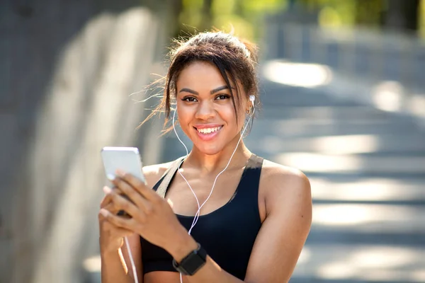 Primo piano della felice donna africana che ascolta musica mentre fa jogging — Foto Stock