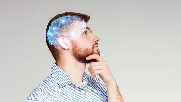 Portrait of thoughtful guy with shining brain on beige background — Stock Photo, Image
