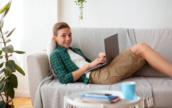 Вид сбоку улыбающегося подростка, болтающего с друзьями на ноутбуке — стоковое фото