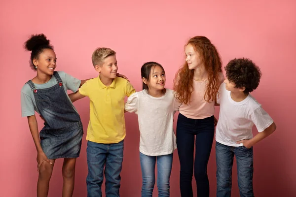 Porträt fröhlicher Schulkinder, die sich vor rosa Hintergrund anschauen — Stockfoto