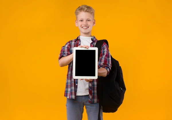 Gülümseyen okul çocuğu kameraya tablet ekranı gösteriyor — Stok fotoğraf