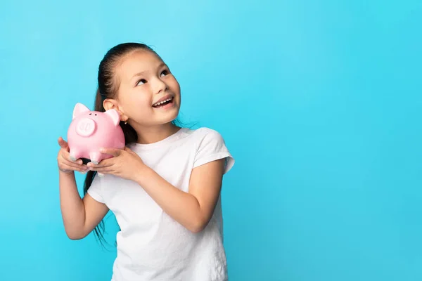 Menina com banco porquinho, tiro estúdio, espaço livre — Fotografia de Stock