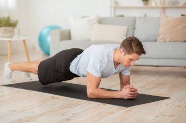 Genç adam spor için evine git. Atlet mindere tahta çakıyor.