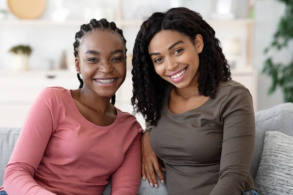 Glada svarta tjejer sitter tillsammans på soffan — Stockfoto