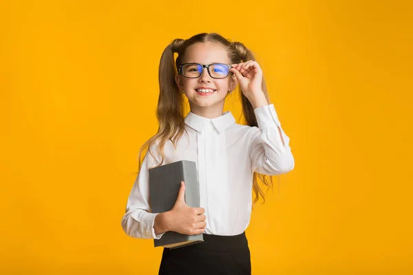 Malá dívka drží knihu pózování na žlutém pozadí studia — Stock fotografie