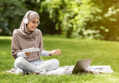 Parkta internetten bilgisayar kullanan Arap bir kız.