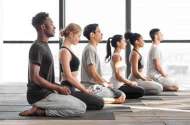 Yoga yapan ve stüdyoda meditasyon yapan mutlu kadın ve erkekler.