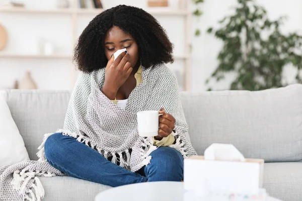 Sick afro girl wrapped in blanket drinking hot tea — Stock Photo, Image