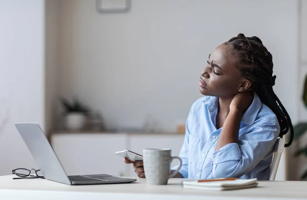 Уставшая чернокожая деловая женщина, страдающая от боли в шее после долгого дня в офисе — стоковое фото